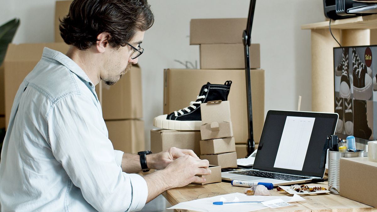 Businessman packing products and managing an online store from his desk with a laptop