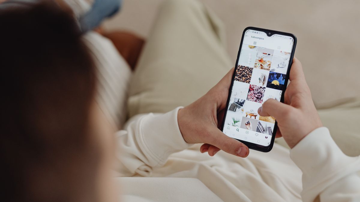 Person using smartphone to browse Instagram indoors, showing social media engagement