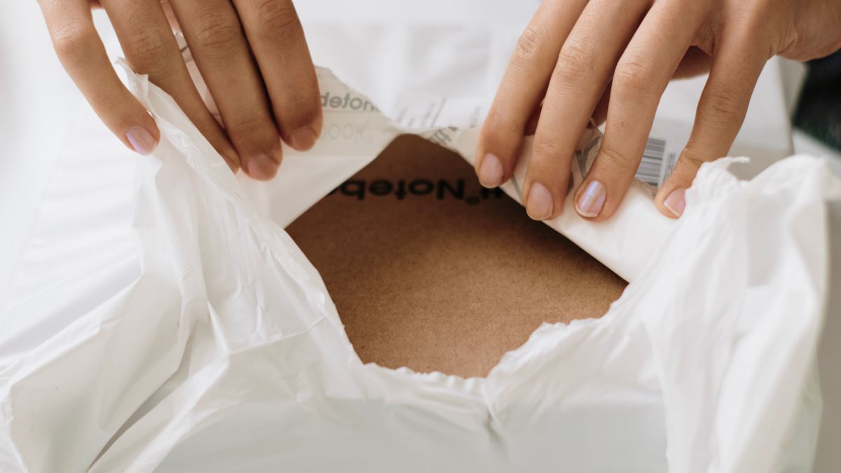 Hands carefully opening a white package to reveal contents inside. Perfect for unboxing themes