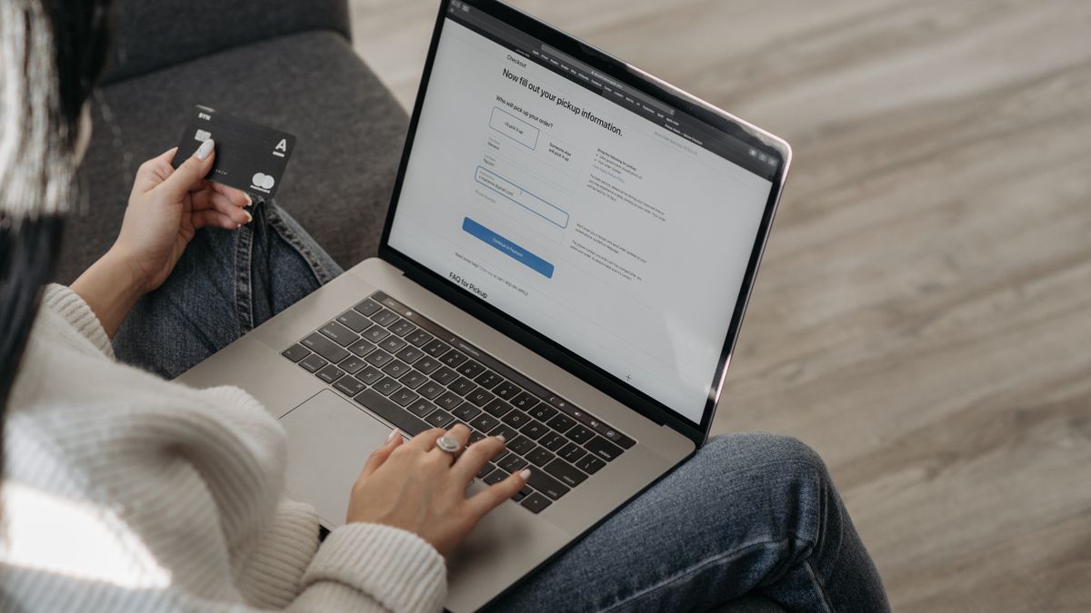 Close-up of a woman using a laptop for online shopping and holding a credit card in hand