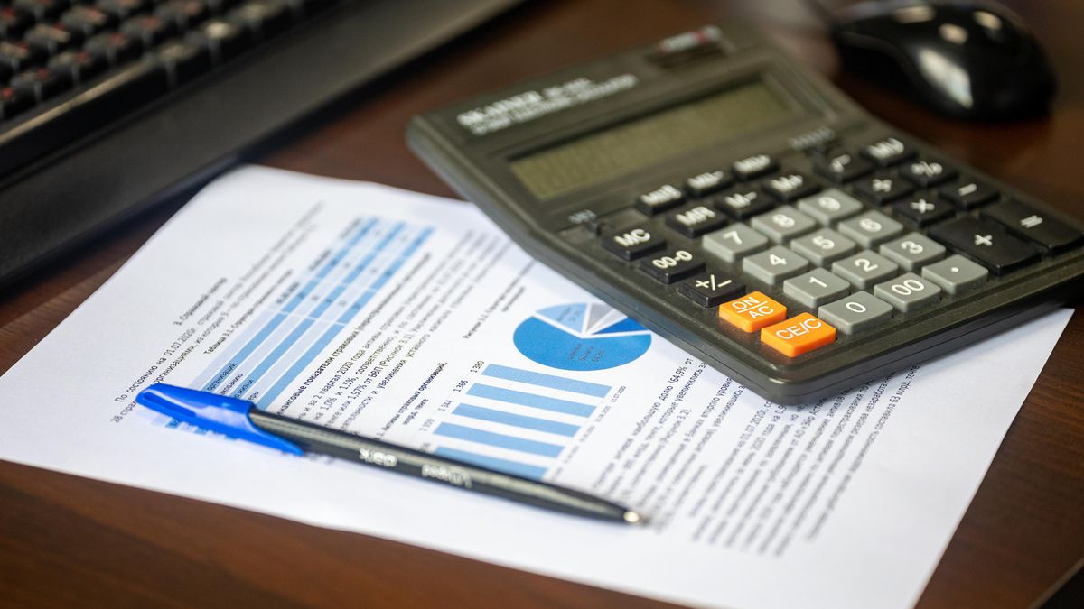Desk with calculator, financial report, and pen, suggesting business analysis