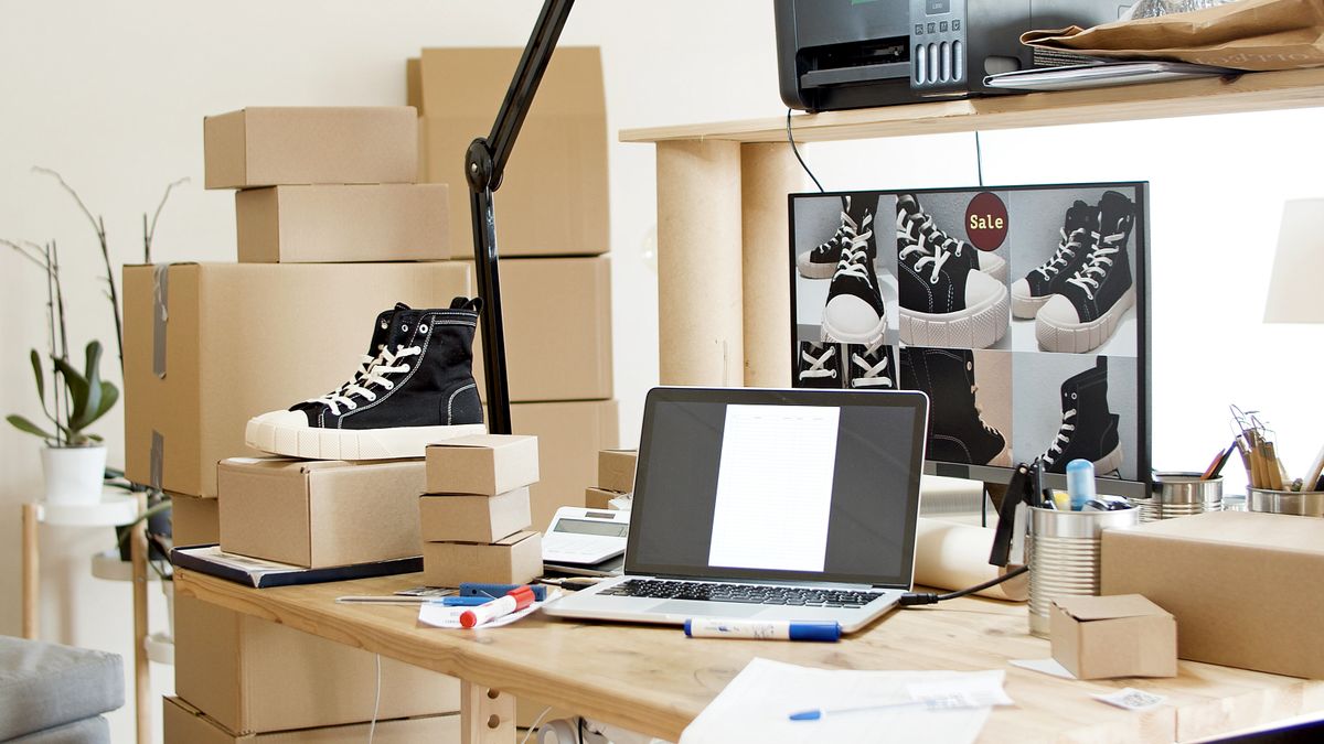 A busy workspace with sneakers, boxes, and a laptop indicating an online shoe store or e-commerce setup