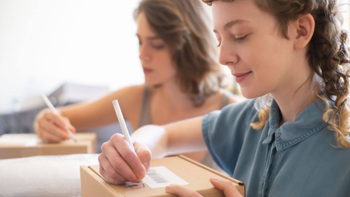 Two women packing boxes for an online store, focusing on barcode and labeling processes