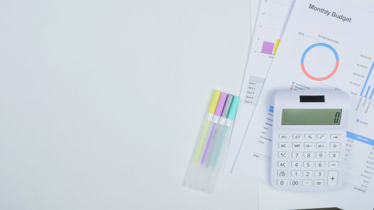 Minimalist office desk with a calculator, budget planning documents, and colorful pens