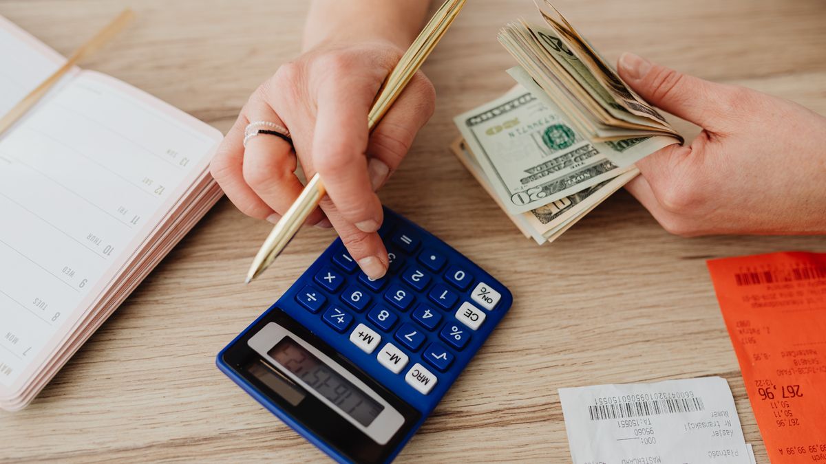 Hands handling cash and calculator for budget planning. Modern financial scene