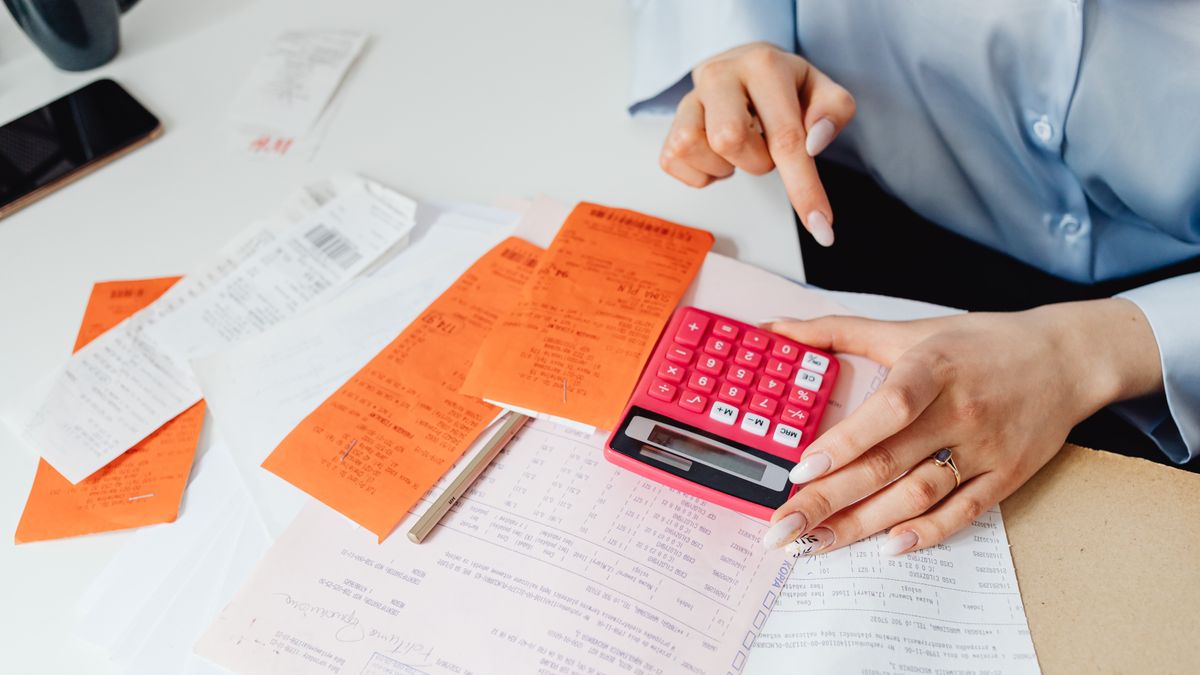 Businesswoman calculates expenses using receipts and calculator at desk. Ideal for finance, accounting themes