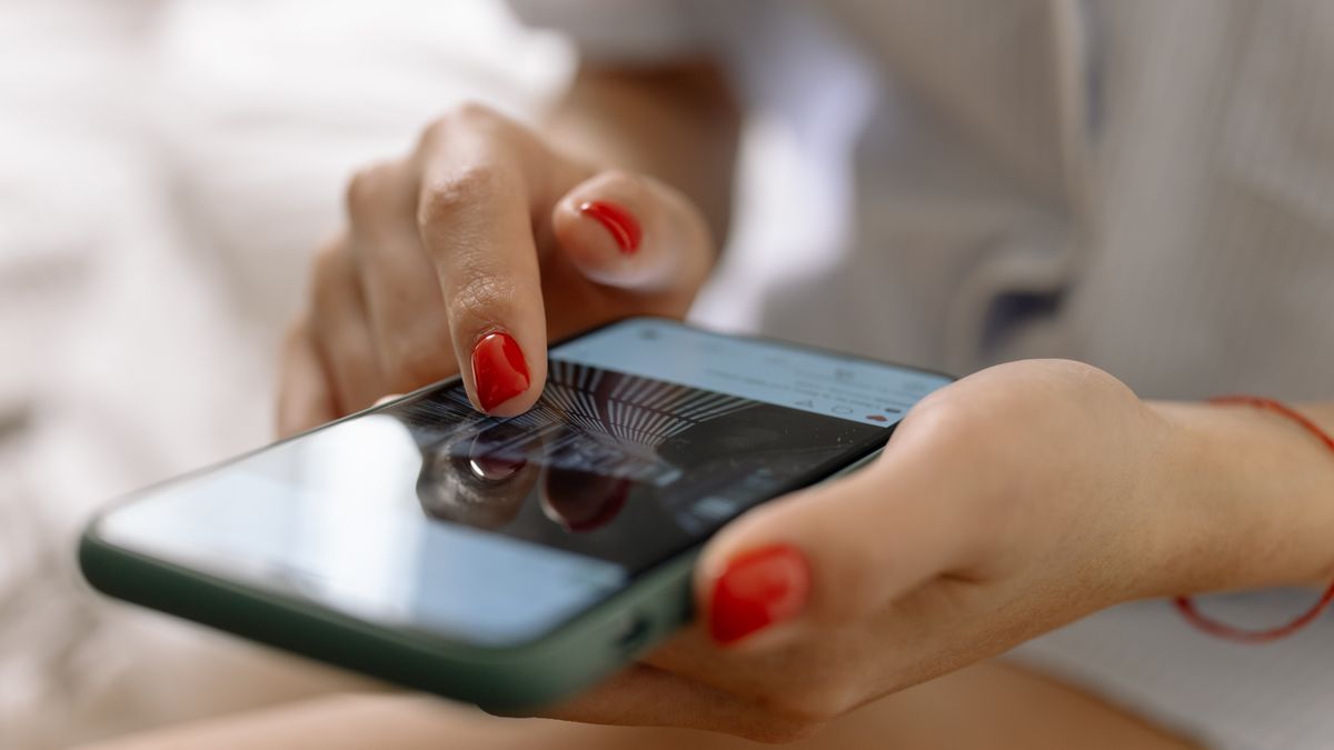 A person with red nails using a smartphone with a touch screen interface