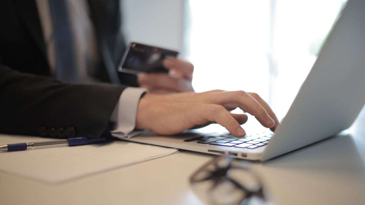 Man in suit using laptop and credit card for online transaction at work