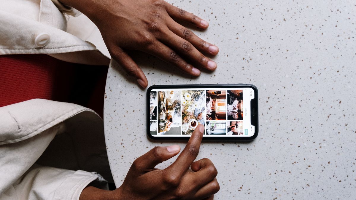 Close-up of hands using a smartphone on a cafe table, browsing social media or photos
