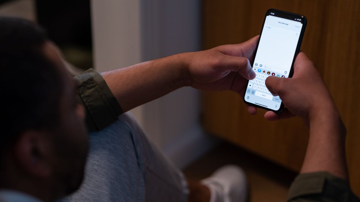 Close-up of a man texting on a smartphone indoors during evening time. Captures modern communication