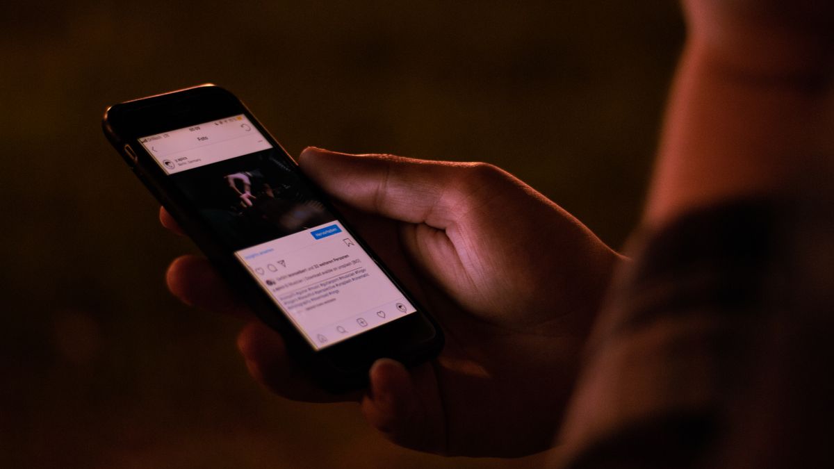 A person interacts with a smartphone in a dimly lit setting, emphasizing mobile technology usage