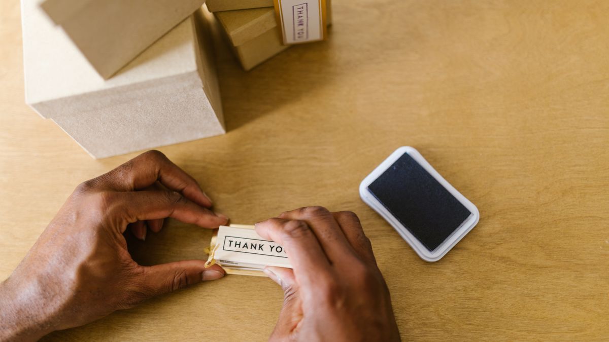 Hands of a small business owner sealing thank you cards with an ink pad