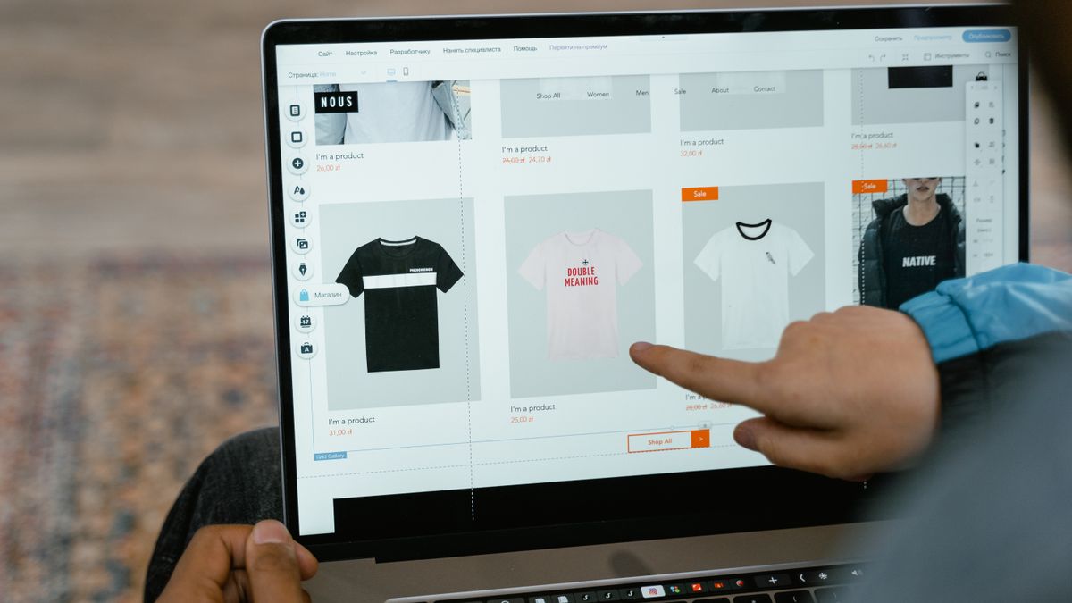 A person points to t-shirt options in an online store on a laptop screen