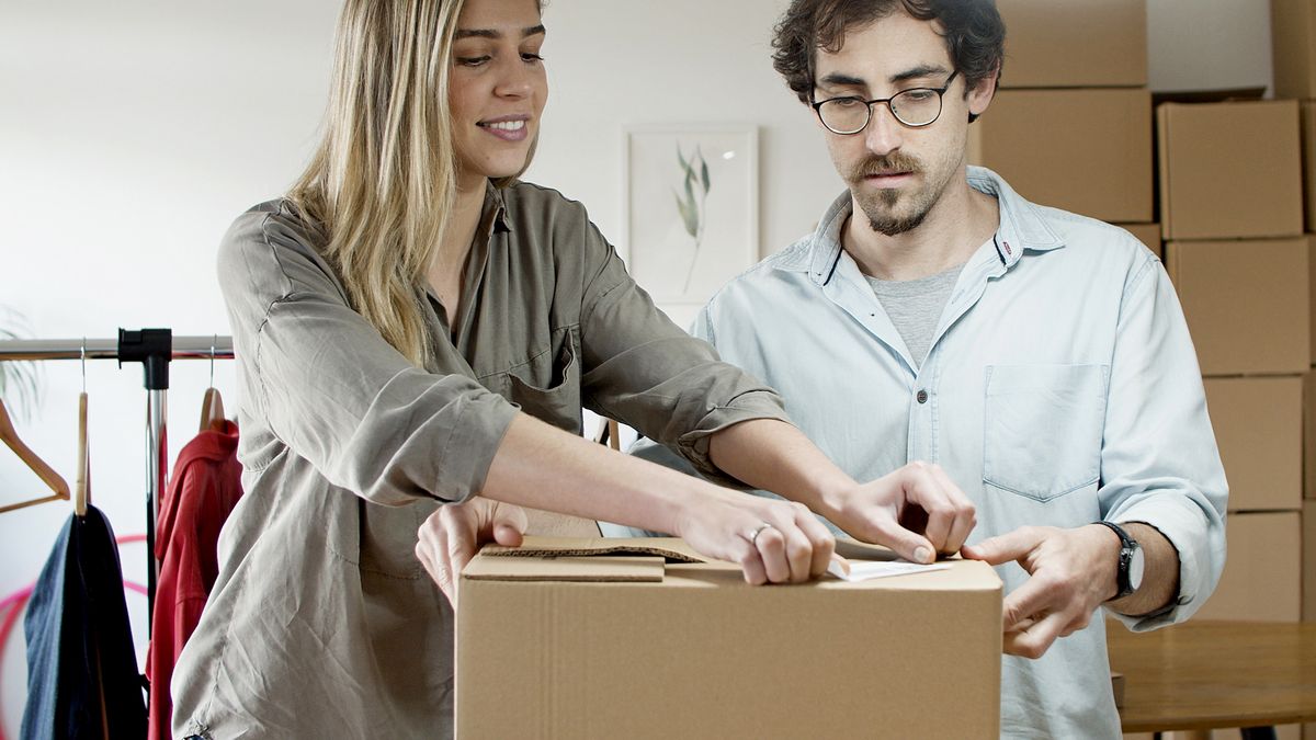 A young man and woman pack boxes in a modern office environment, symbolizing a startup business