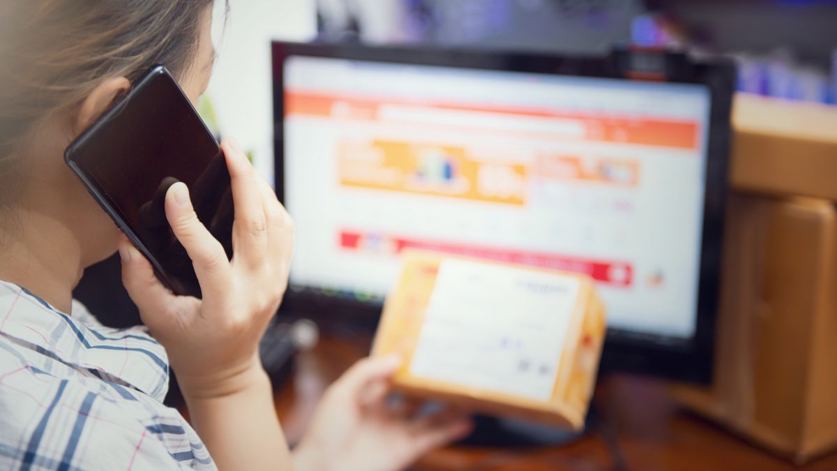 Woman multitasking by using a phone and checking an online purchase package at home