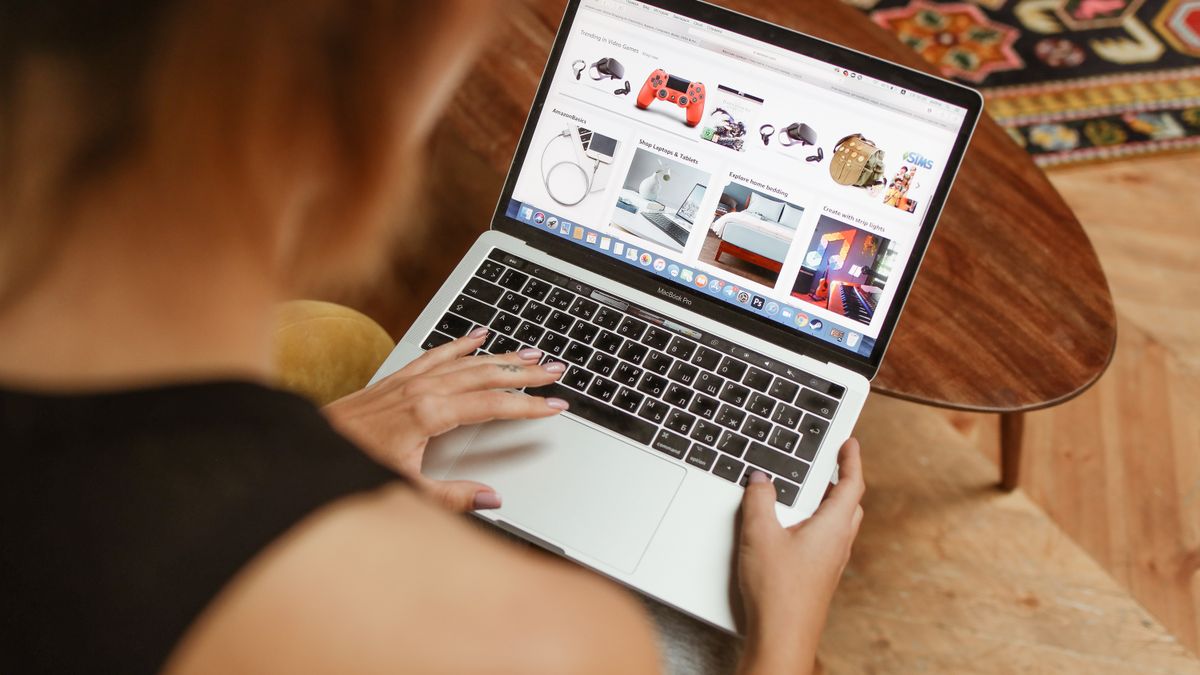 A woman shops online on her laptop while seated in a cozy home environment