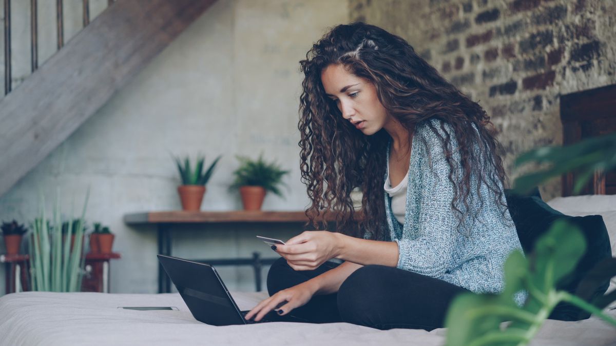 Young woman using laptop and credit card for online shopping at home