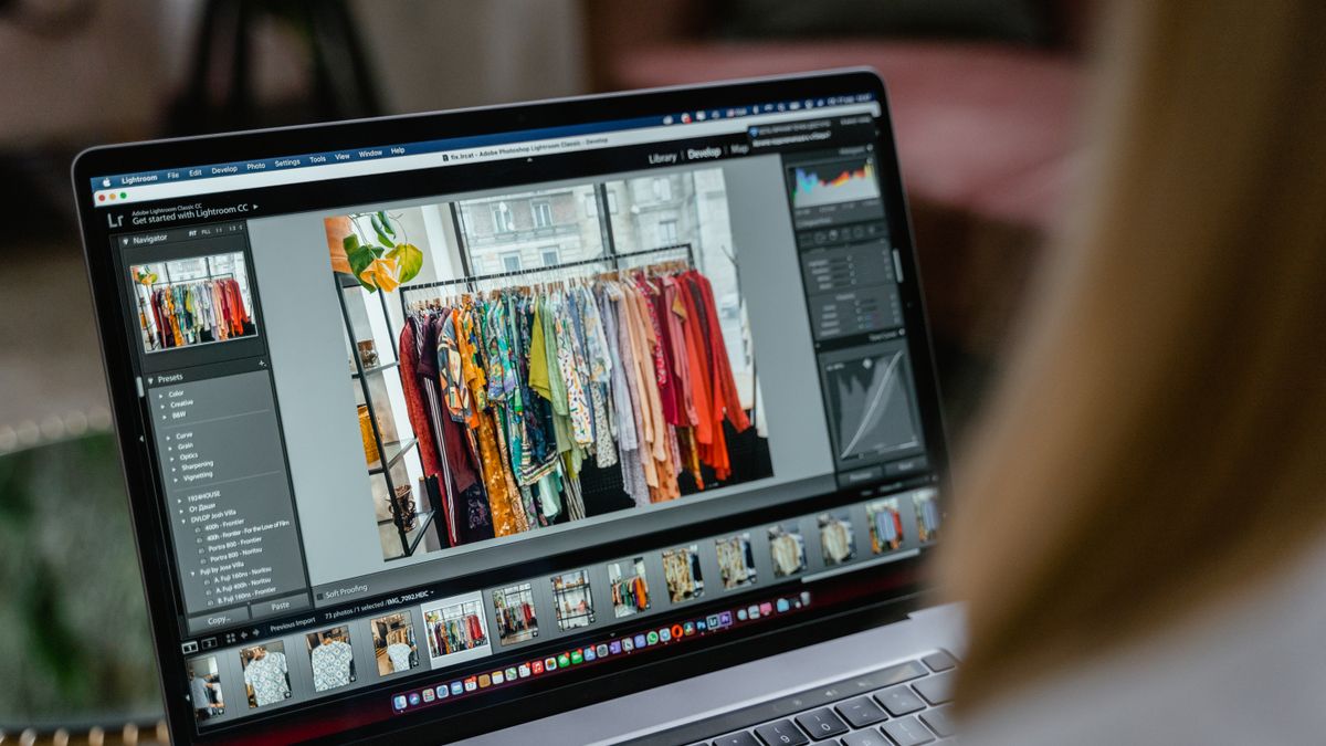 Close-up of a laptop displaying editing software with clothes rack in view