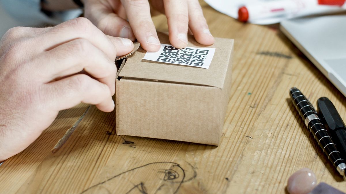 Close-up of hands packing a box with a QR code, symbolizing online business services