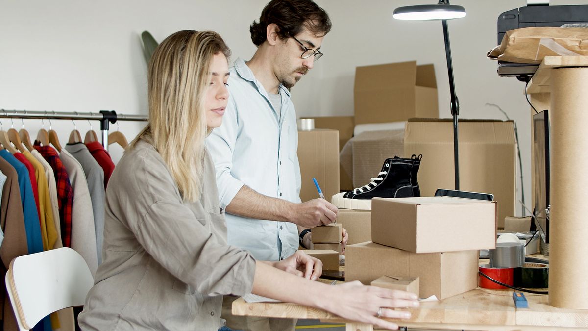 Business partners organizing inventory in an online store setup with clothes and boxes