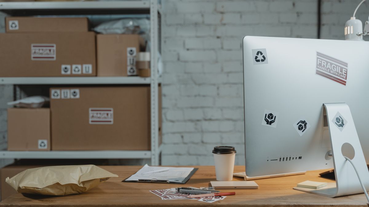 Contemporary office setup with a computer, coffee, and parcels on a wooden desk